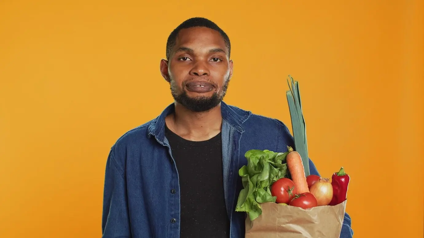 Im Studio spielt eine männliche Person mit einem grünen Apfel herum.